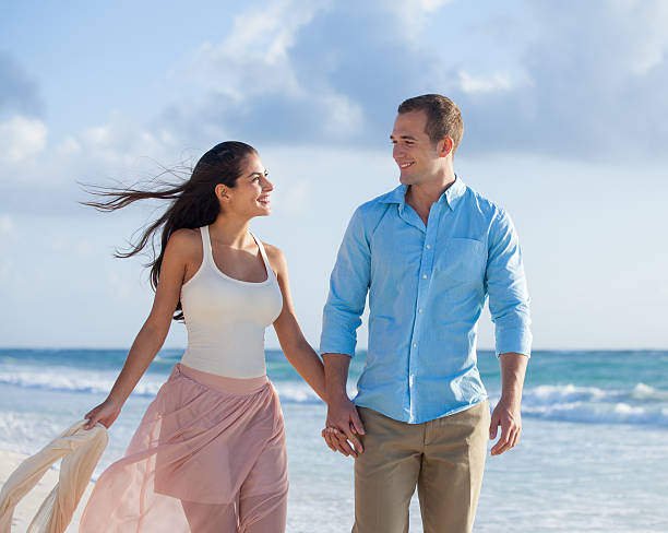 A beautiful couple walking on the beach holding hands in Cancun, Mexico.